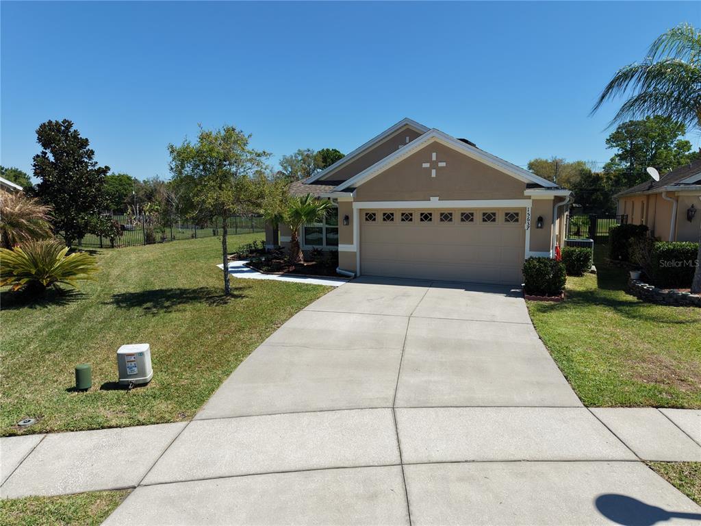 A tan single-story house with a two-car garage and a concrete driveway — 15637 CARINA DR, ORLANDO, FL