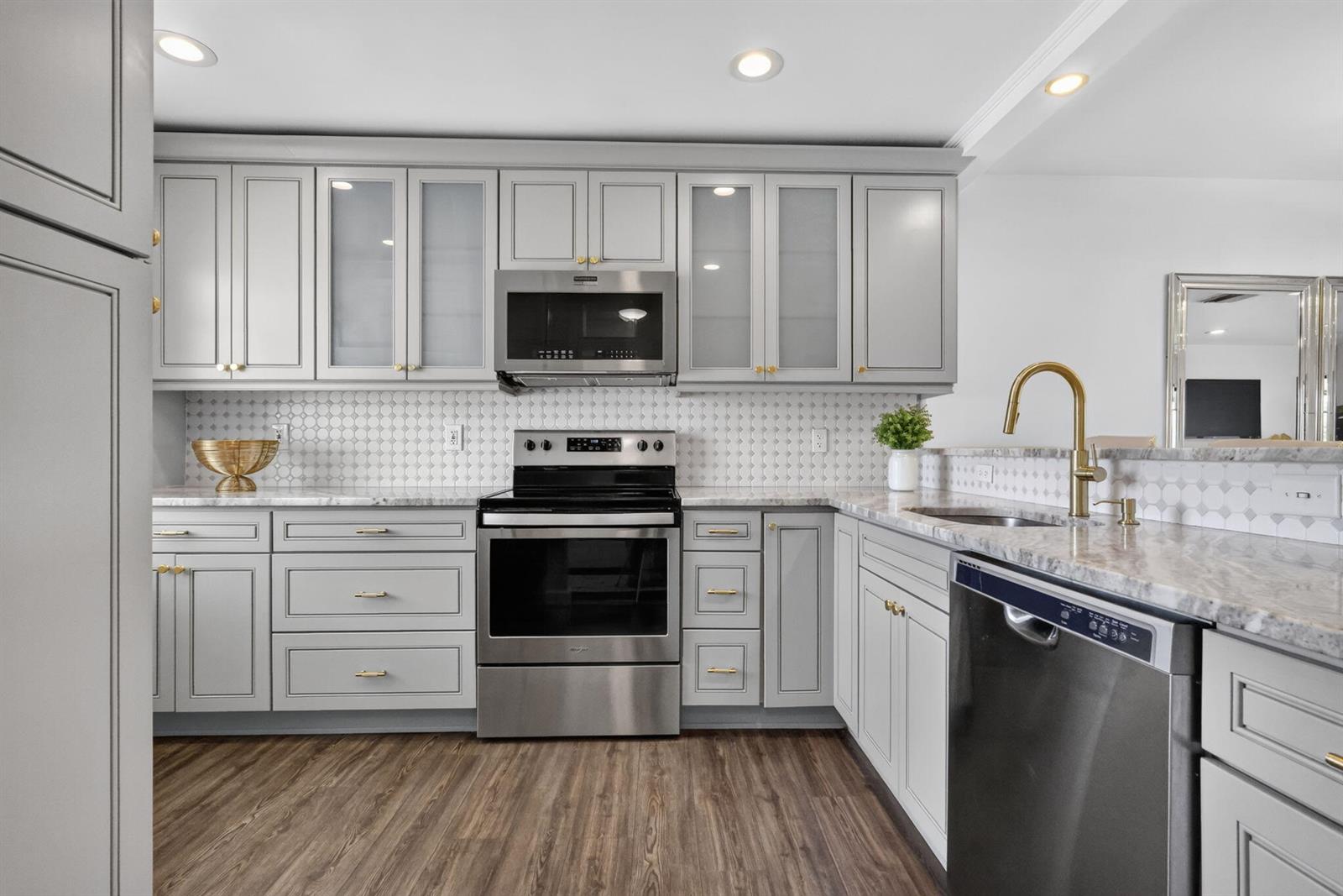 A kitchen features gray cabinets, stainless steel appliances, a marble countertop, and a tiled backsplash — 21219 Lago Circle # 5j, Boca Raton FL 33433, BOCA RATON, FL