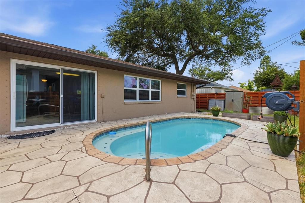A backyard features a swimming pool with a stone patio and a tan house exterior — 541 MORNINGSIDE ROAD, VENICE, FL