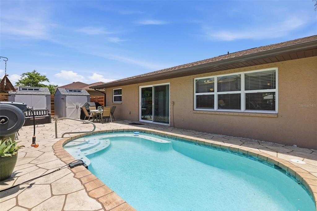 A backyard features a swimming pool with a stone patio and a tan house exterior — 541 MORNINGSIDE ROAD, VENICE, FL