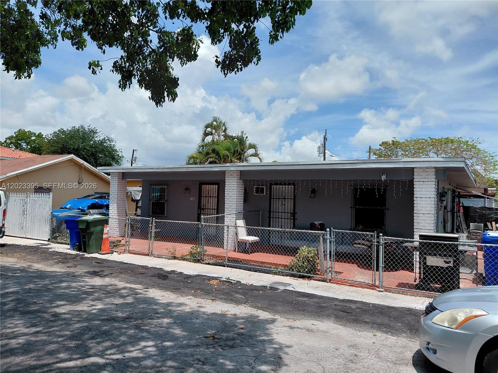 A single-story gray house features a covered porch, white brick pillars, and a chain-link fence — 2140 NW 1st Ter, Miami FL 33125, MIAMI, FL
