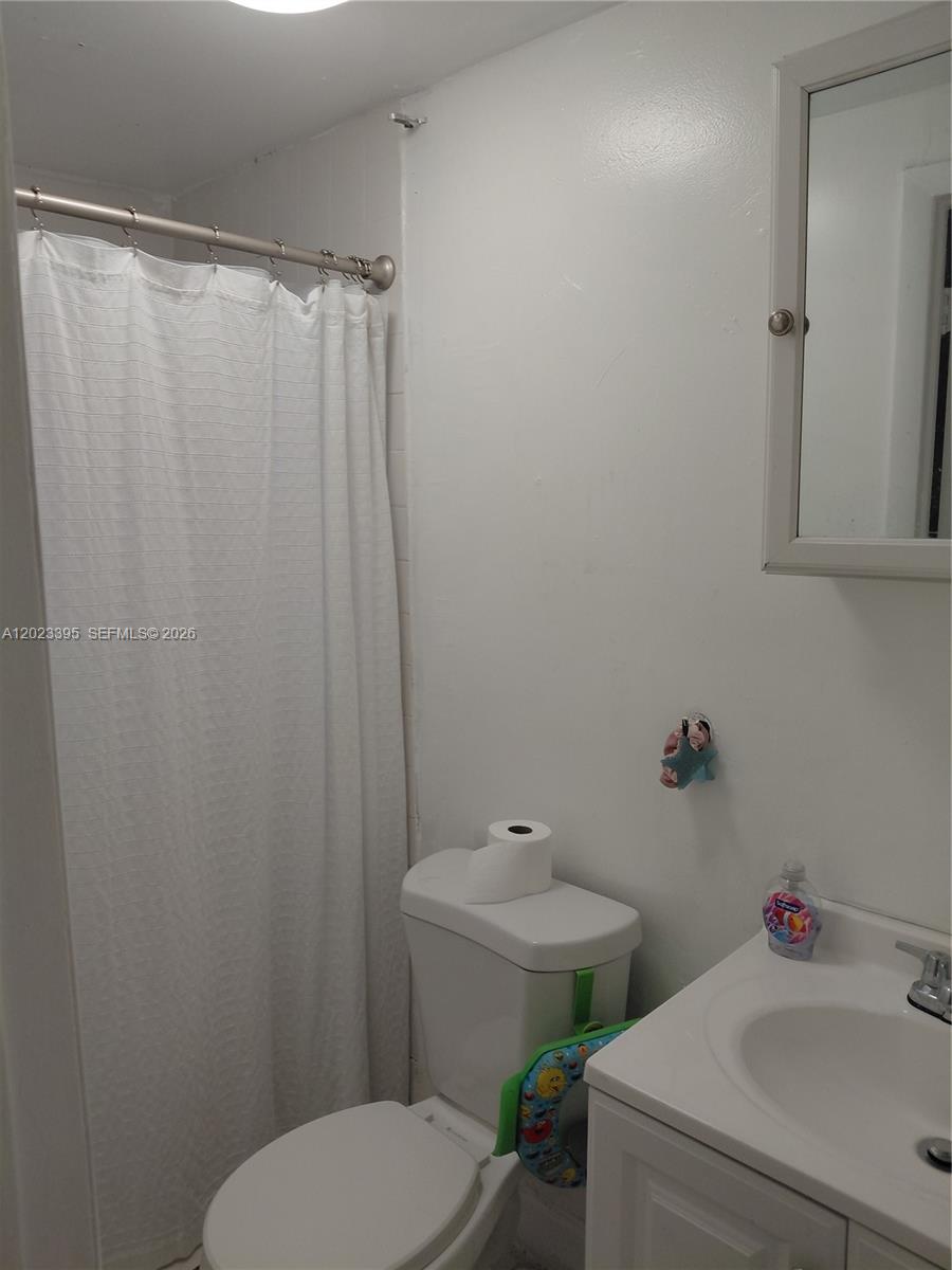 A bathroom features a white vanity, a toilet, and a shower with a white curtain — 2140 NW 1st Ter, Miami FL 33125, MIAMI, FL