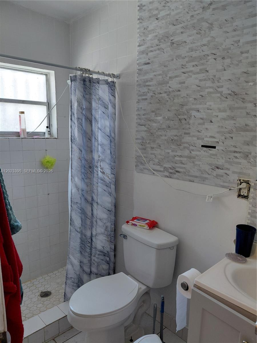 A bathroom features a shower with a marble-patterned curtain, a toilet, and a vanity — 2140 NW 1st Ter, Miami FL 33125, MIAMI, FL