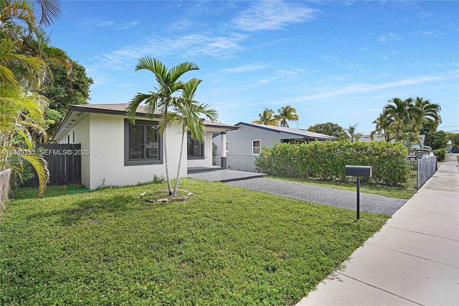 A single-story house with a paved driveway and palm trees sits on a grassy lot — 222 SW 3rd Ter, Dania Beach FL 33004, DANIA BEACH, FL