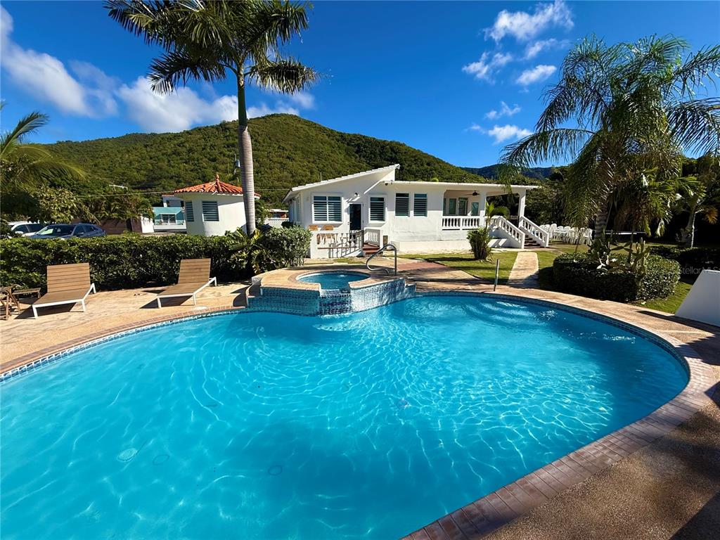 A swimming pool and hot tub sit in front of a white house with palm trees — Carr #3 BEACH FRONT GUEST HOUSE, PATILLAS, PR