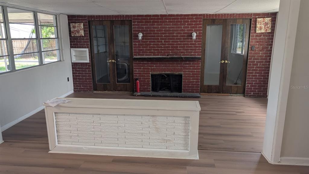A room with wood-look flooring, a red brick fireplace, and a white brick-fronted counter — 714 GOVERNORS AVENUE, ORLANDO, FL
