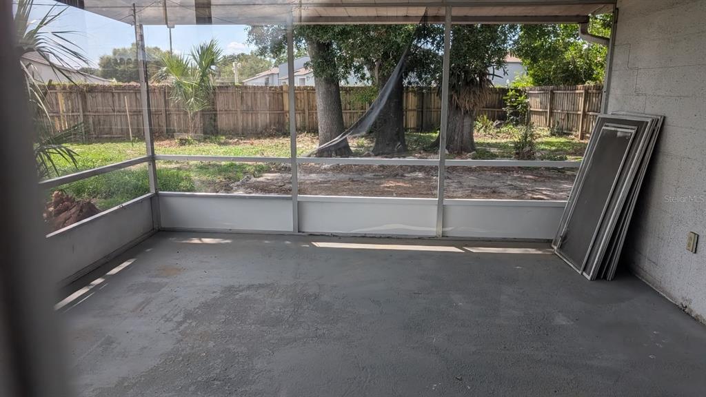 A screened-in porch with a concrete floor looking out onto a fenced backyard with trees — 714 GOVERNORS AVENUE, ORLANDO, FL