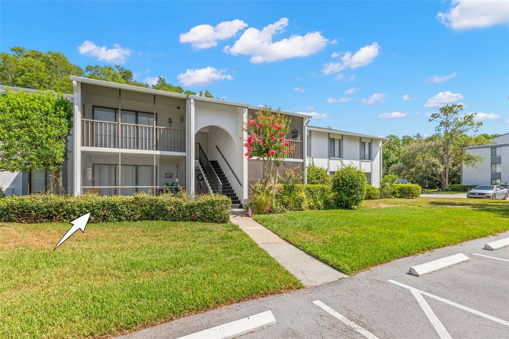 A two-story apartment building with screened balconies and a central staircase exterior — 1290 PINE RIDGE CIRCLE E UNIT E1, TARPON SPRINGS, FL