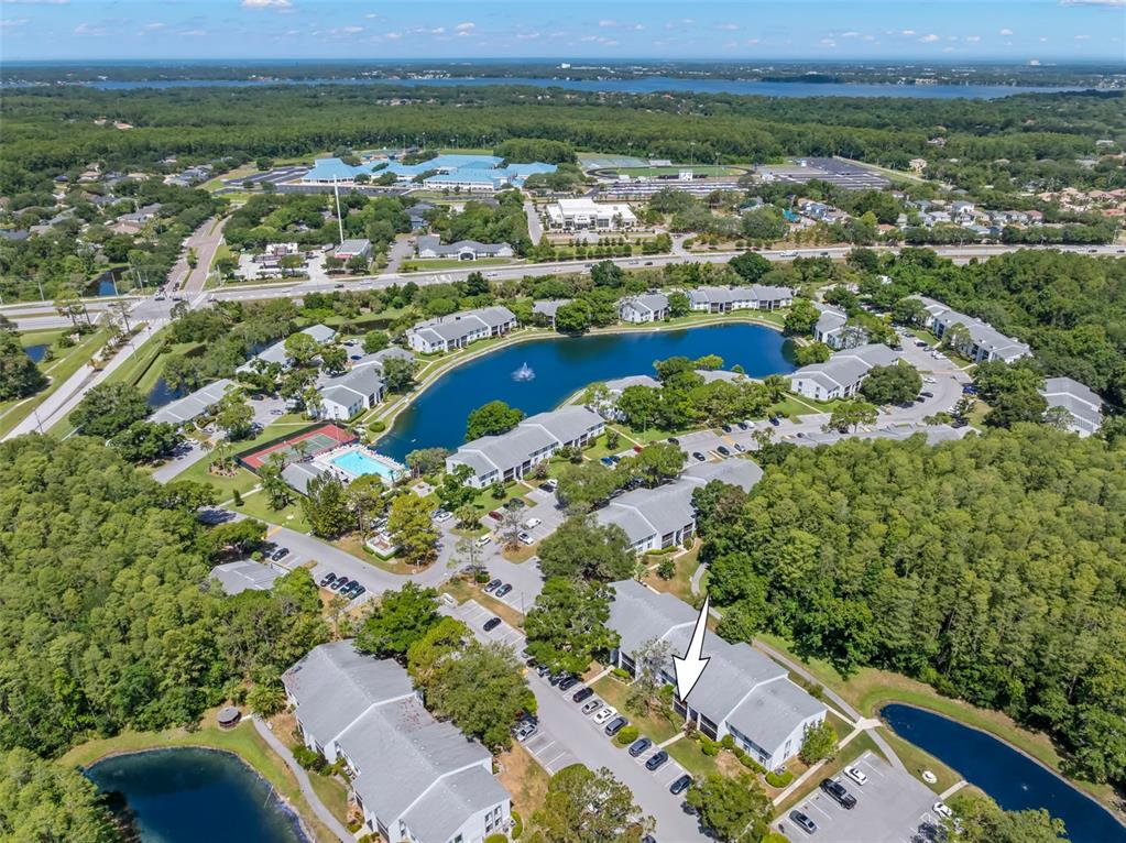 An aerial view shows a multi-building apartment complex surrounding a central pond and fountain — 1290 PINE RIDGE CIRCLE E UNIT E1, TARPON SPRINGS, FL