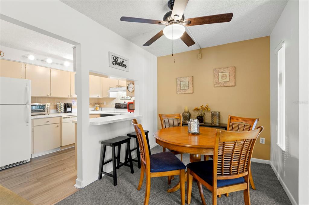 A dining area with a round wooden table, chairs, and a pass-through to the kitchen — 1290 PINE RIDGE CIRCLE E UNIT E1, TARPON SPRINGS, FL