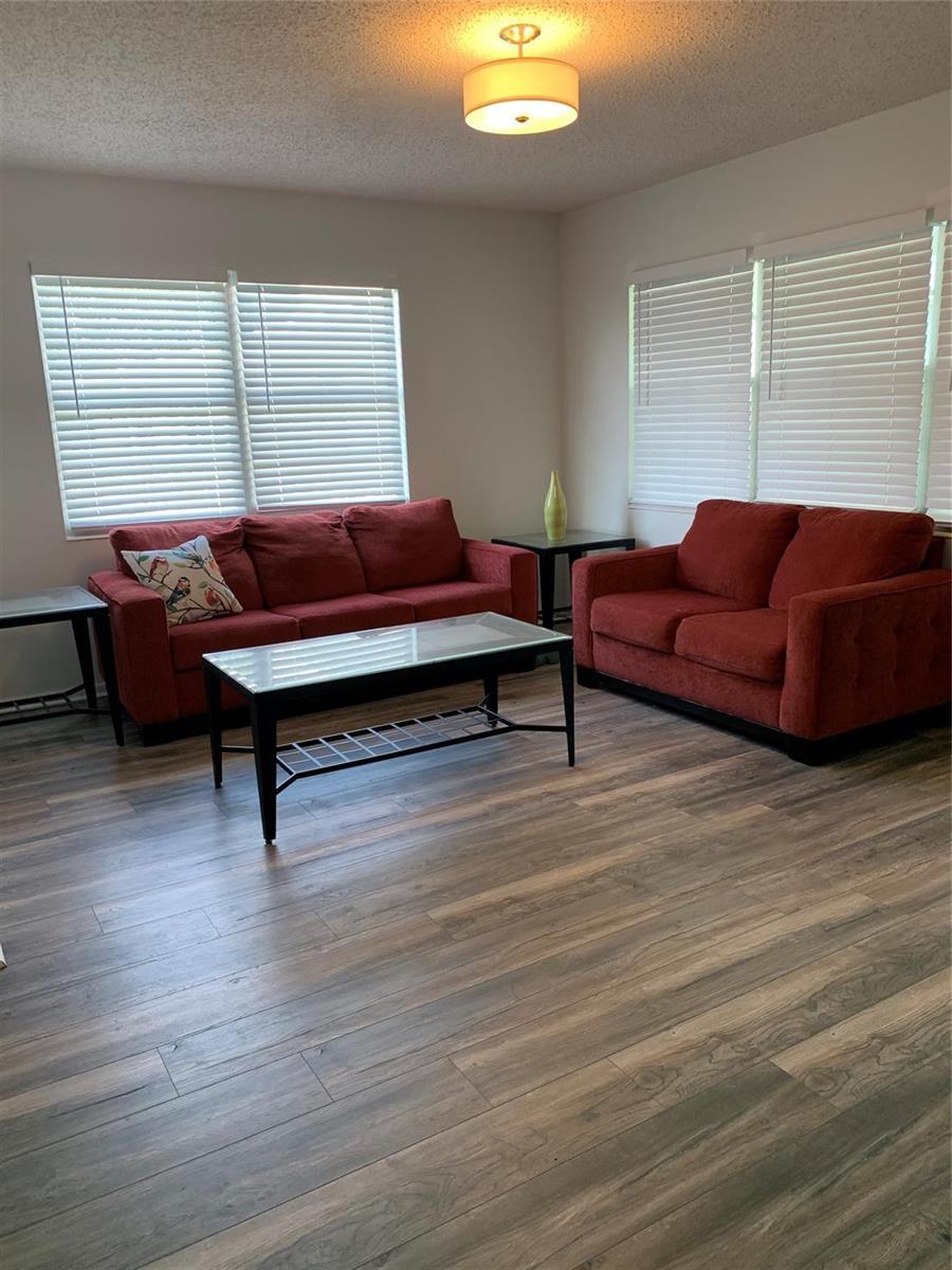 A living room features two red sofas, a glass-top coffee table, and wood-look flooring — 236 Prescott-l # 236, Deerfield Beach FL 33442, DEERFIELD BEACH, FL