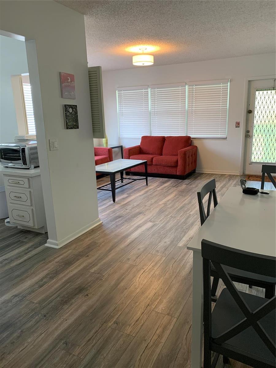 A living room with wood-look flooring, a red sofa, and a glass-topped coffee table — 236 Prescott-l # 236, Deerfield Beach FL 33442, DEERFIELD BEACH, FL