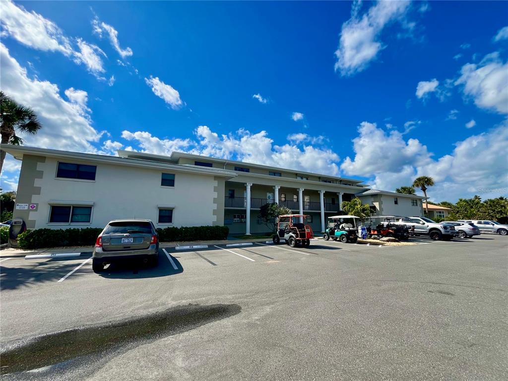 A multi-story apartment building with a parking lot, golf carts, and vehicles in front — 2100 N PENINSULA AVENUE UNIT 2160, NEW SMYRNA BEACH, FL