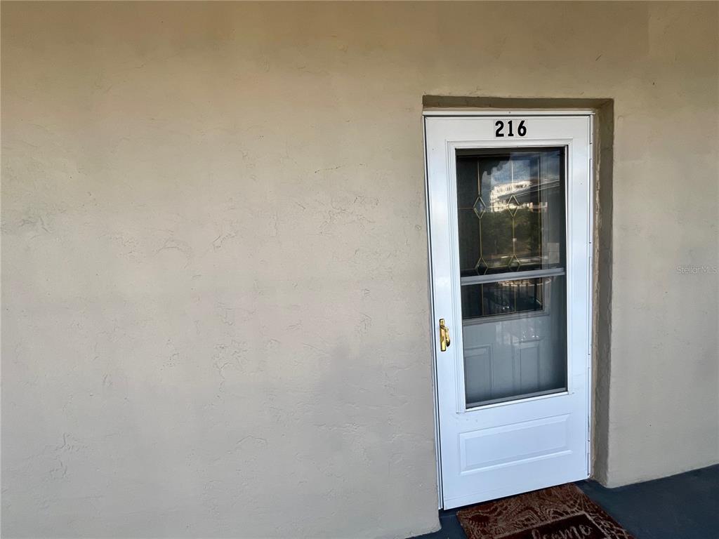 A white storm door with the number 216 is set into a beige stucco wall — 2100 N PENINSULA AVENUE UNIT 2160, NEW SMYRNA BEACH, FL