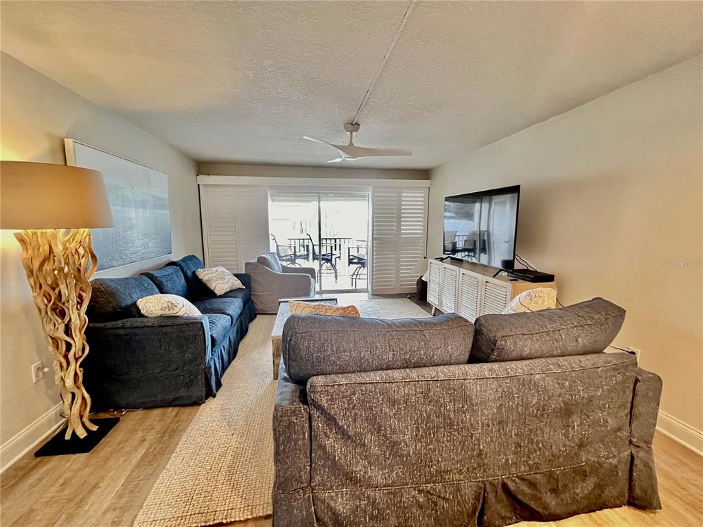 A living room features two dark sofas, a television on a cabinet, and a floor lamp — 2100 N PENINSULA AVENUE UNIT 2160, NEW SMYRNA BEACH, FL