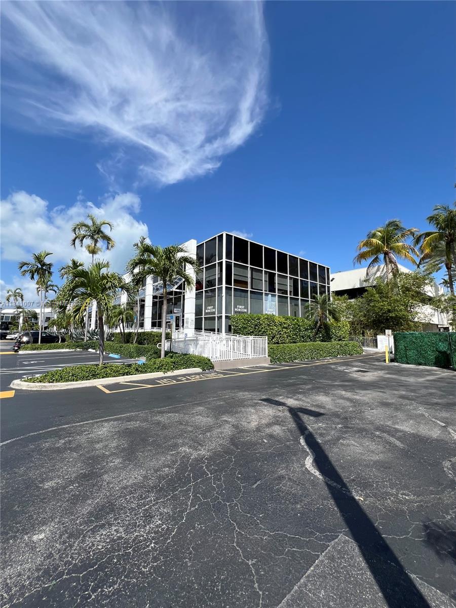 A two-story commercial building with dark glass windows stands in a parking lot with palm trees — 260 Crandon Blvd # A51, Key Biscayne FL 33149, KEY BISCAYNE, FL