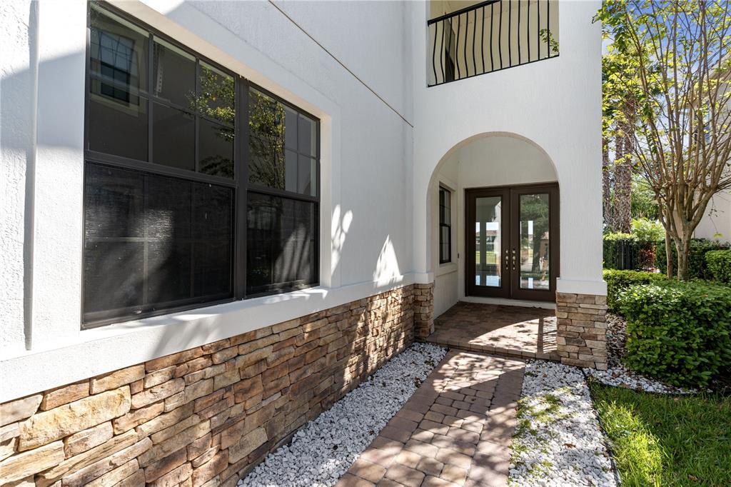 A stone-accented exterior wall features a large window and an arched entryway with double doors — 13019 WOODFORD STREET, ORLANDO, FL