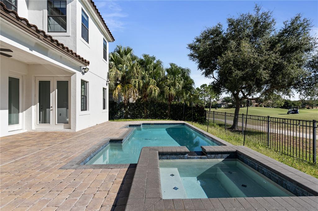 A backyard features a rectangular swimming pool, an attached spa, and a paved patio area — 13019 WOODFORD STREET, ORLANDO, FL