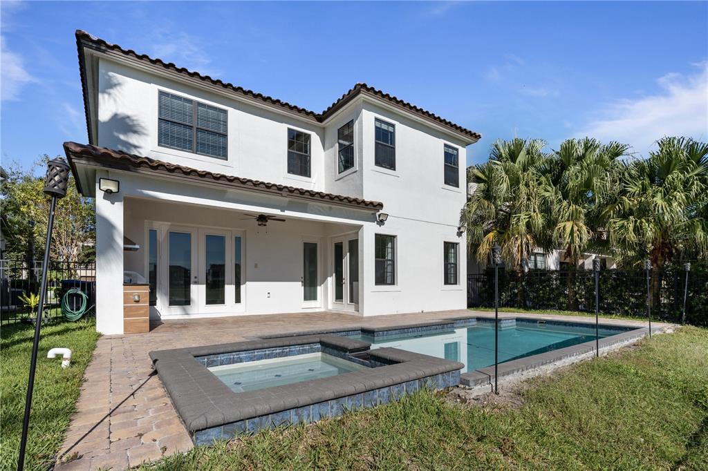 A two-story white house with a tiled roof, a covered patio, and a backyard pool — 13019 WOODFORD STREET, ORLANDO, FL
