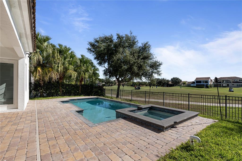 A backyard patio features a swimming pool, a raised spa, and a view of a golf course — 13019 WOODFORD STREET, ORLANDO, FL