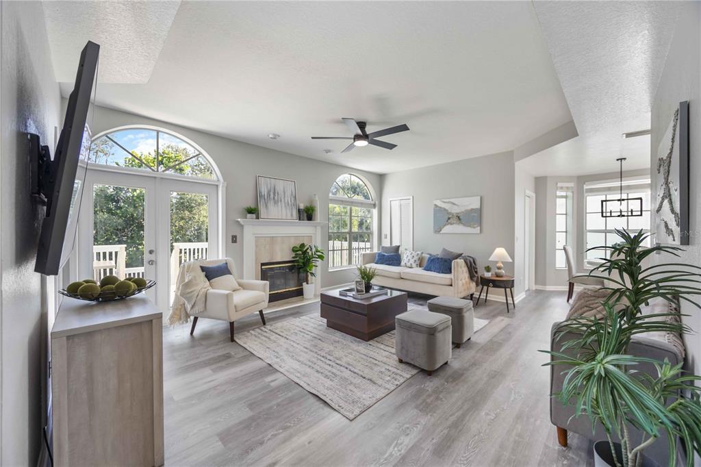 A living room features light wood-look flooring, a fireplace, arched windows, and a ceiling fan — 13951 HARBOR VIEW DRIVE, SEMINOLE, FL