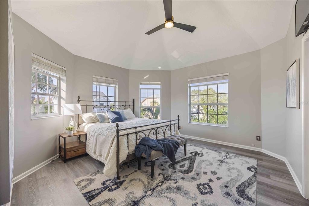 A bedroom with a metal bed frame, gray flooring, and multiple windows under a ceiling fan — 13951 HARBOR VIEW DRIVE, SEMINOLE, FL