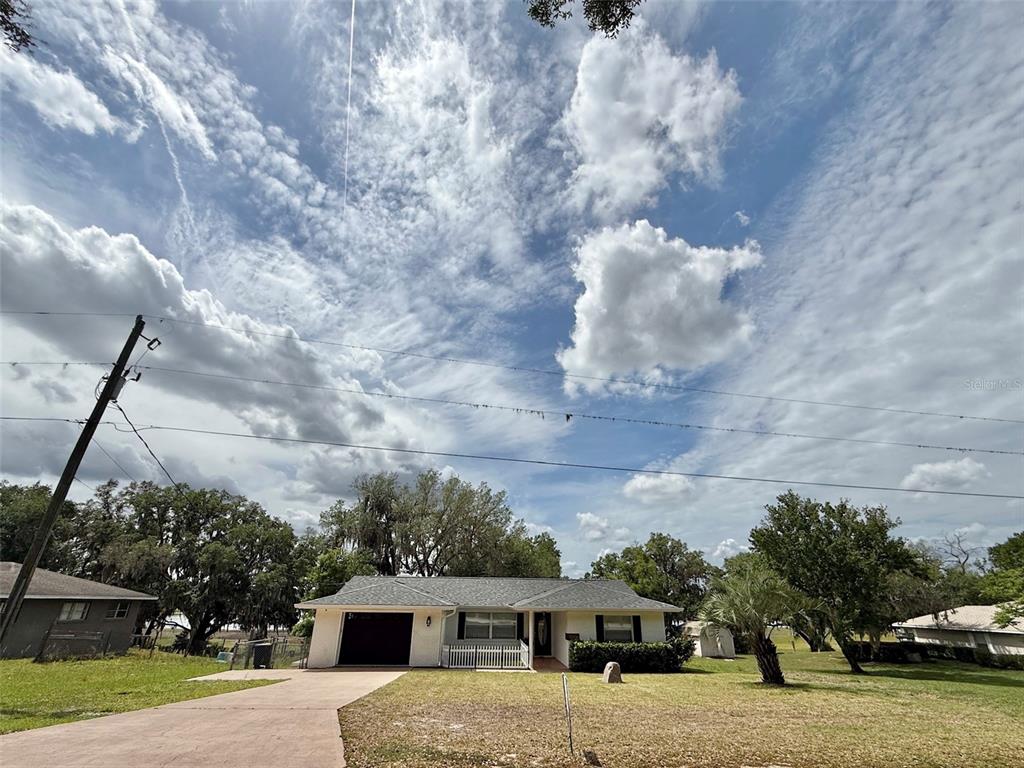 A single-story house with a garage and a white fence under a cloudy sky — 3824 SW SHOREWOOD DRIVE, DUNNELLON, FL