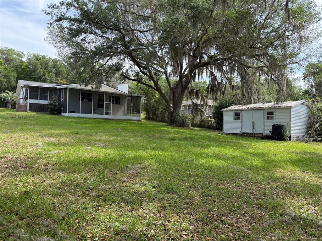 A backyard features a house with a screened porch, a shed, and a large oak tree — 3824 SW SHOREWOOD DRIVE, DUNNELLON, FL