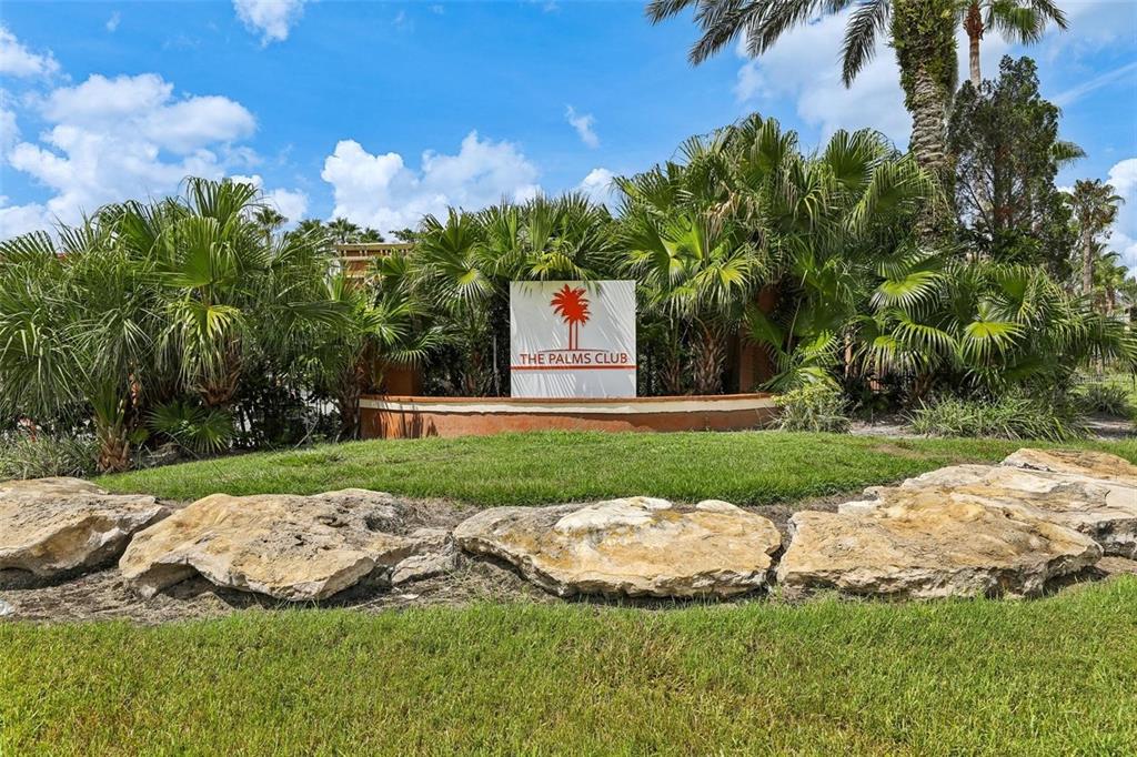 A sign for The Palms Club stands behind large rocks in a landscaped garden area — 5554 METROWEST BOULEVARD UNIT 4-310, ORLANDO, FL