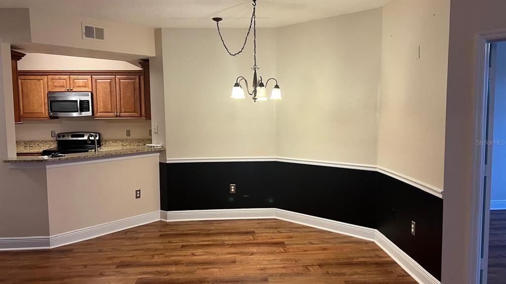 A dining area features wood-look flooring, a chandelier, and walls painted with a black wainscot — 5554 METROWEST BOULEVARD UNIT 4-310, ORLANDO, FL