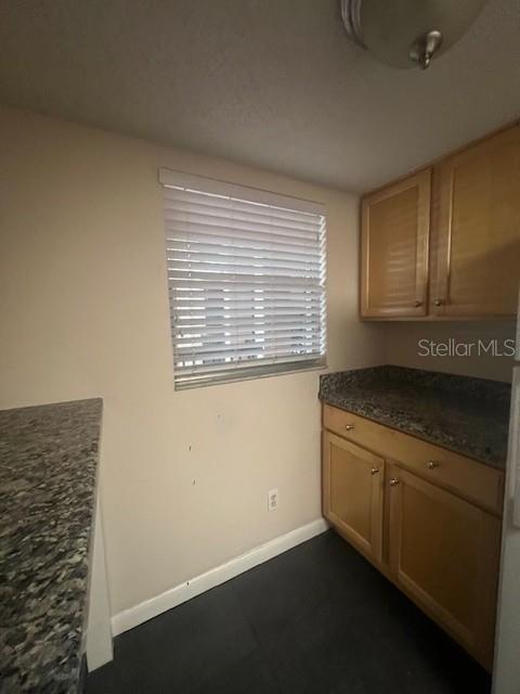 A kitchen features wood cabinets, granite countertops, a stainless steel sink, and an adjacent laundry area — 3700 S OSPREY AVENUE UNIT 221, SARASOTA, FL