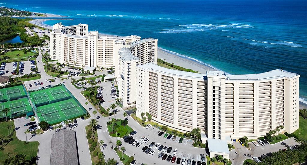 An aerial view of a large, curved beachfront apartment complex with tennis courts and parking — 400 Ocean Trail Way # 203, Jupiter FL 33477, JUPITER, FL