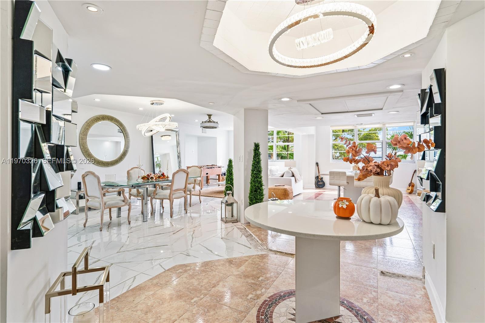 A bright, open-concept living and dining area features marble flooring, modern chandeliers, and decorative mirrors — 905 Brickell Bay Dr # 230, Miami FL 33131, MIAMI, FL