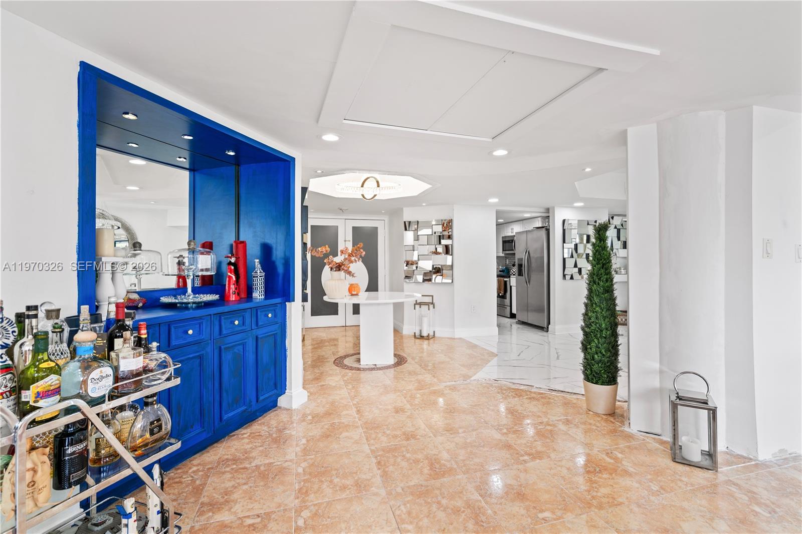 A bright room features a vibrant blue built-in bar, marble floors, and a modern chandelier — 905 Brickell Bay Dr # 230, Miami FL 33131, MIAMI, FL