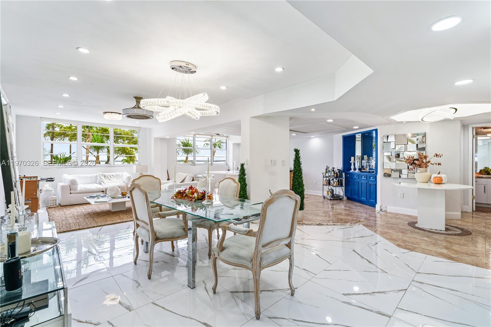 A dining area with a glass table and white chairs sits before a bright living room — 905 Brickell Bay Dr # 230, Miami FL 33131, MIAMI, FL