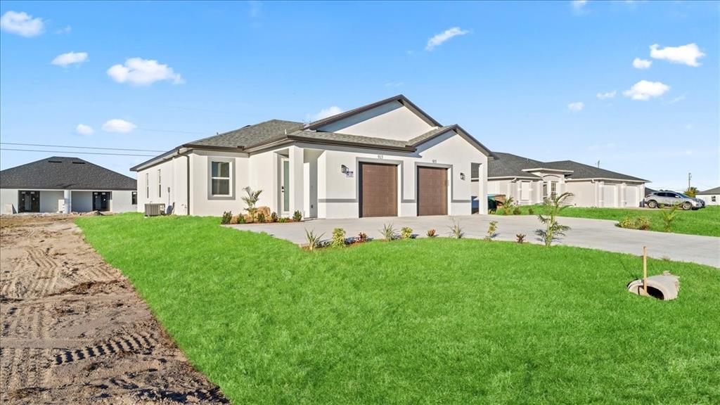 A modern duplex with a concrete driveway and a freshly sodded lawn under a blue sky — 826/828 DIPLOMAT PARKWAY E, CAPE CORAL, FL