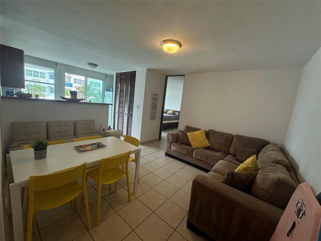 A living and dining area features tile floors, a brown sectional sofa, and yellow chairs — Km 7 EL CHARLIE UNIT NE204, LOIZA, PR