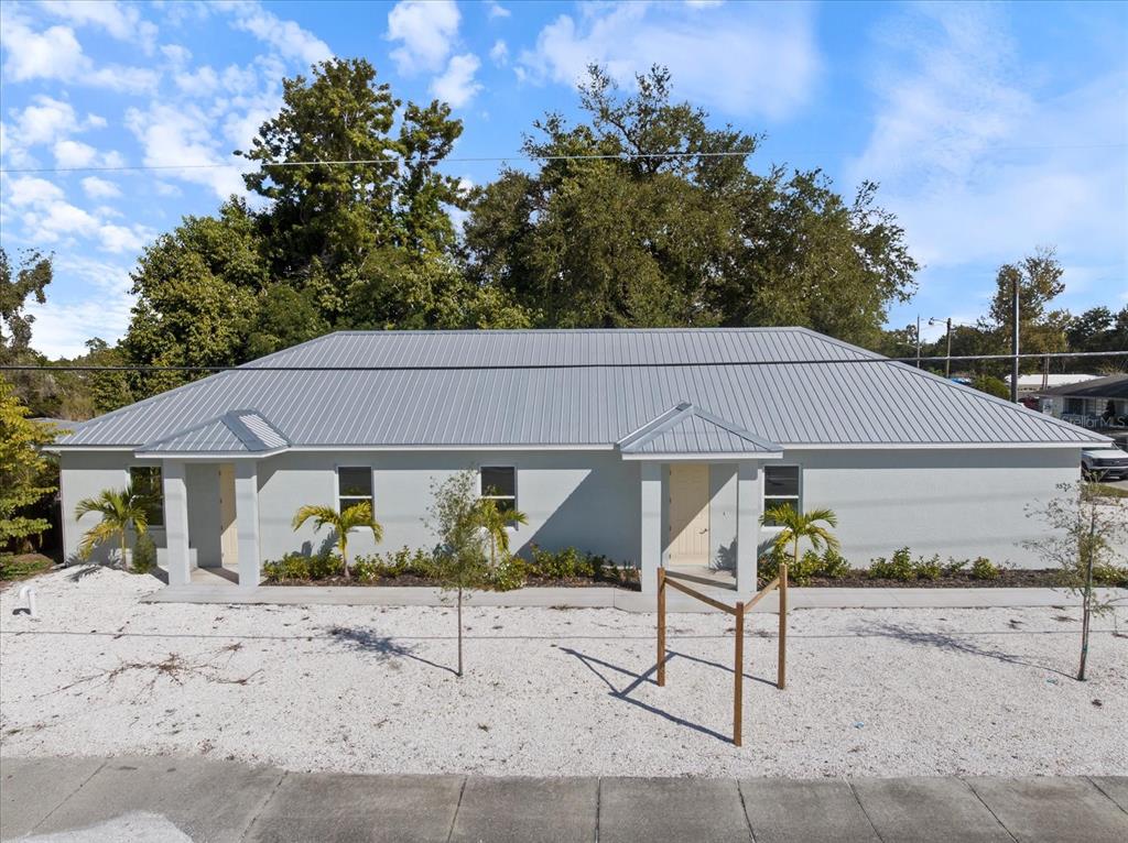 A single-story duplex with a gray metal roof and light-colored stucco exterior — 3525 MCINTOSH ROAD, SARASOTA, FL