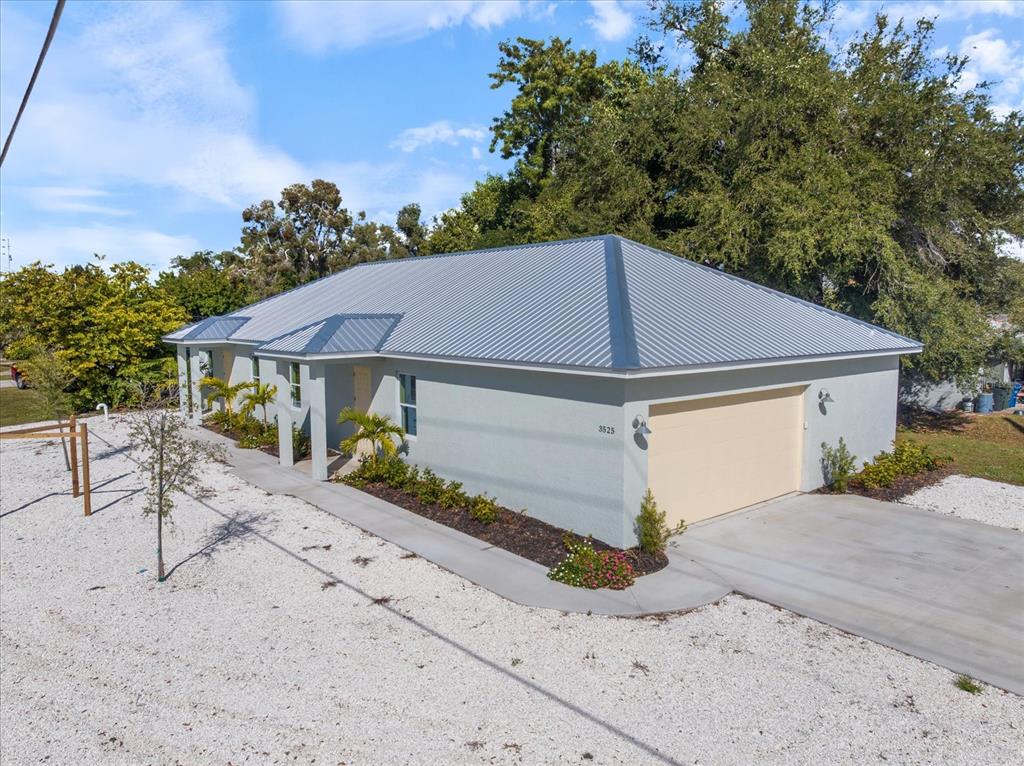 An exterior view of a single-story house with a metal roof and a gravel yard — 3525 MCINTOSH ROAD, SARASOTA, FL