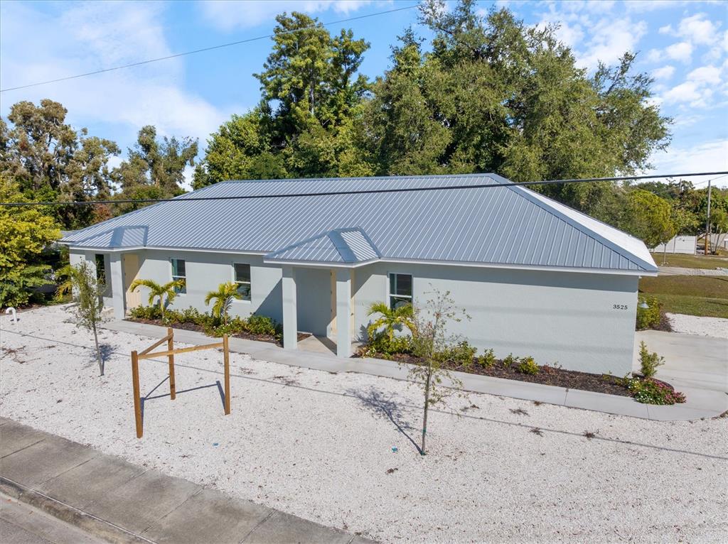 A single-story house with a light gray exterior, metal roof, and gravel front yard — 3525 MCINTOSH ROAD, SARASOTA, FL