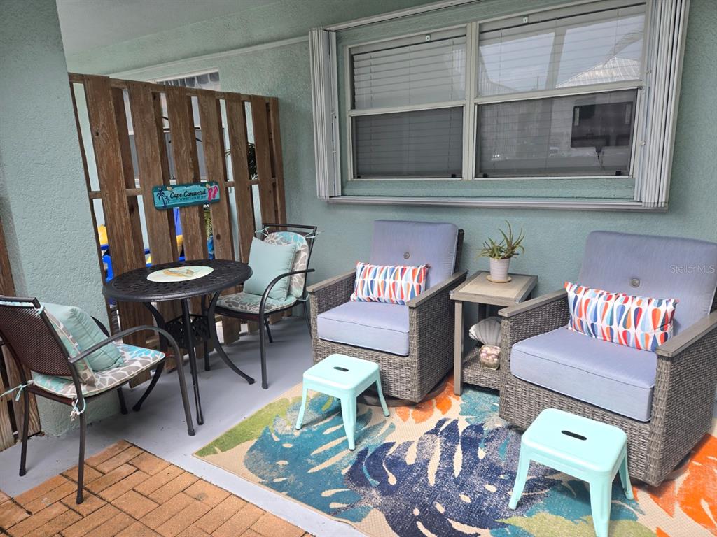 A patio features a small table, two armchairs, two stools, and a patterned area rug — 7605 RIDGEWOOD AVENUE UNIT 11-1, CAPE CANAVERAL, FL