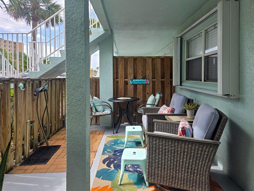 A covered patio features wicker chairs, a small table, and a wooden privacy fence — 7605 RIDGEWOOD AVENUE UNIT 11-1, CAPE CANAVERAL, FL