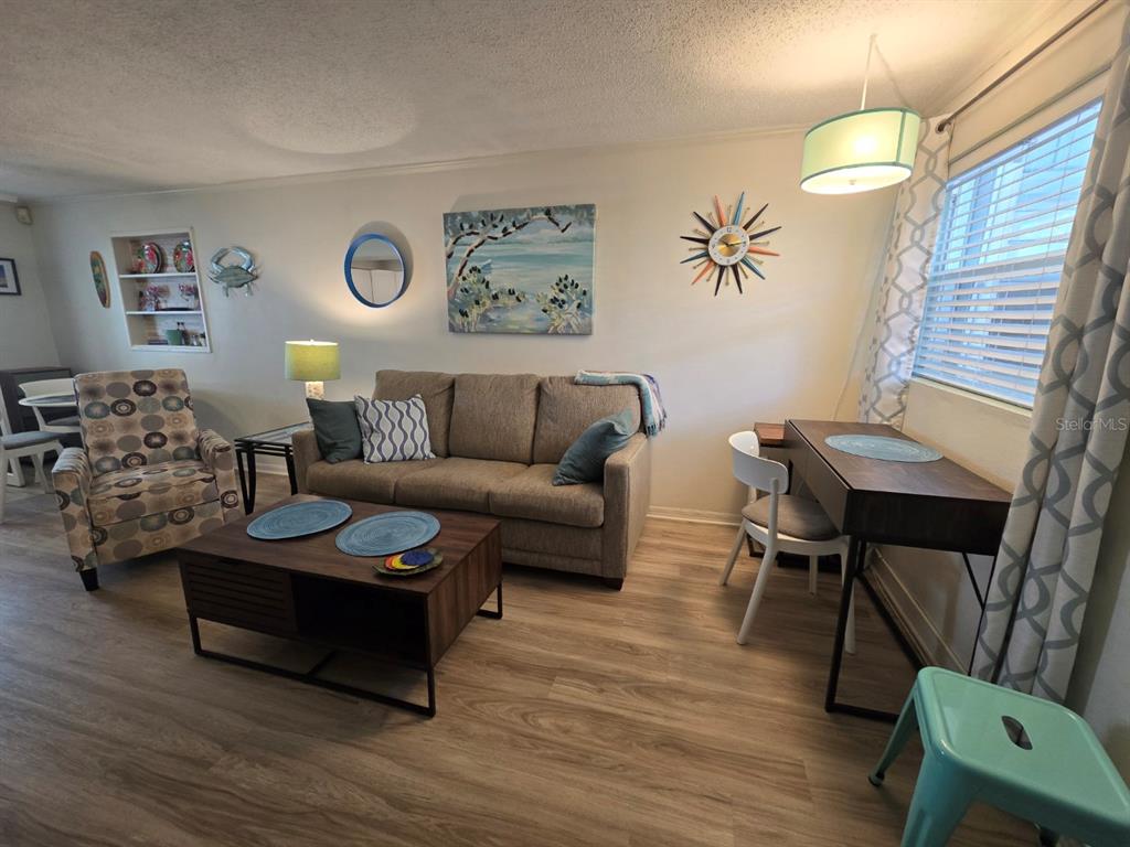 A living room features a beige sofa, patterned armchair, wood coffee table, and dining desk — 7605 RIDGEWOOD AVENUE UNIT 11-1, CAPE CANAVERAL, FL
