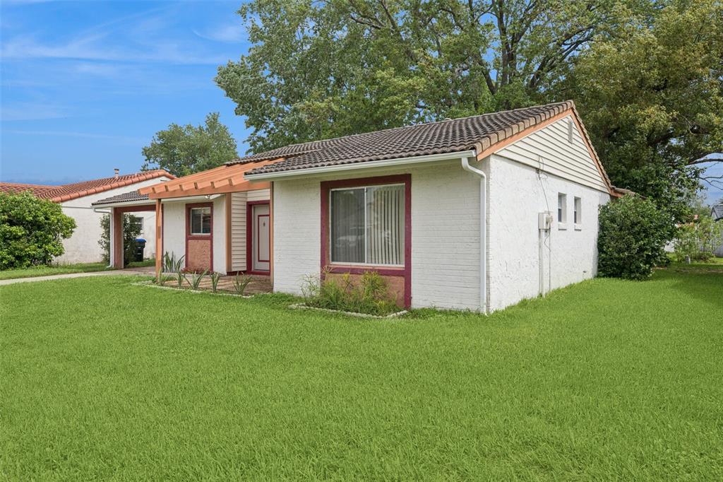 A single-story white brick house with a tiled roof and a small front patio — 10113 MUSKET LANE, ORLANDO, FL