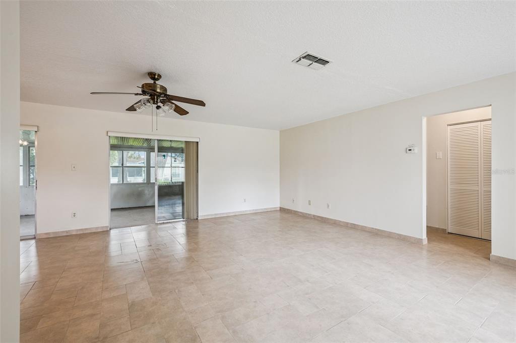 A bright living room features light tile flooring, a ceiling fan, and sliding glass doors — 10113 MUSKET LANE, ORLANDO, FL