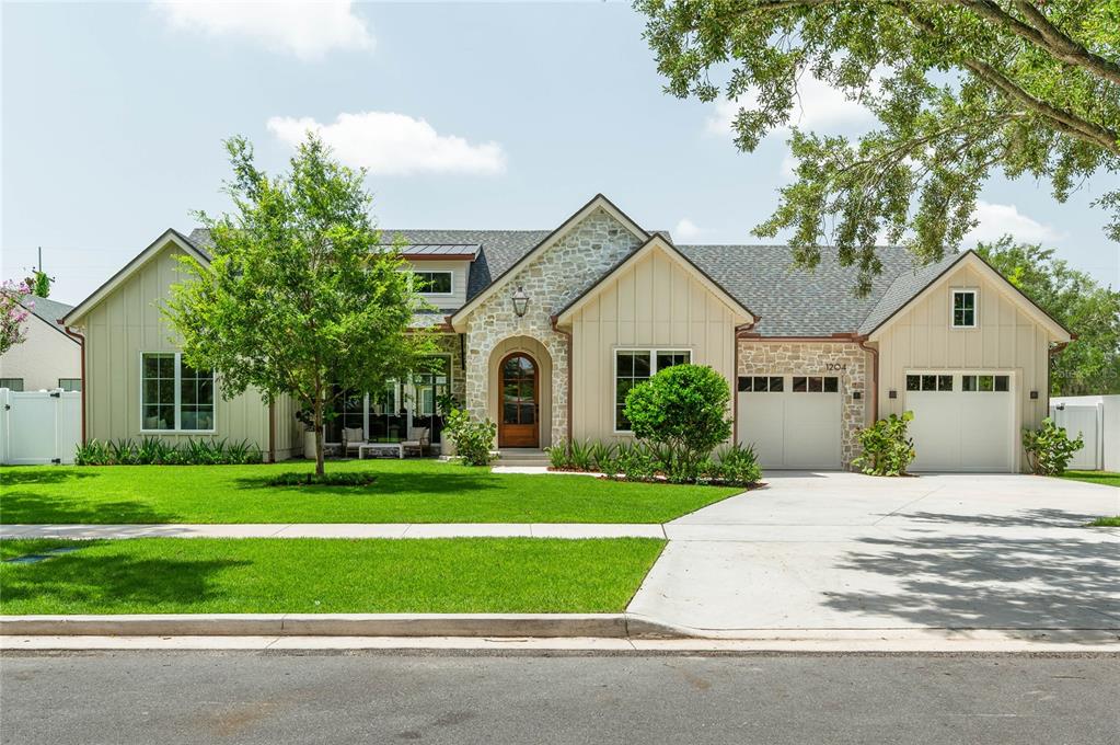 A single-story house with board-and-batten siding, stone accents, a two-car garage, and a front lawn — 1204 NOTTINGHAM STREET, ORLANDO, FL