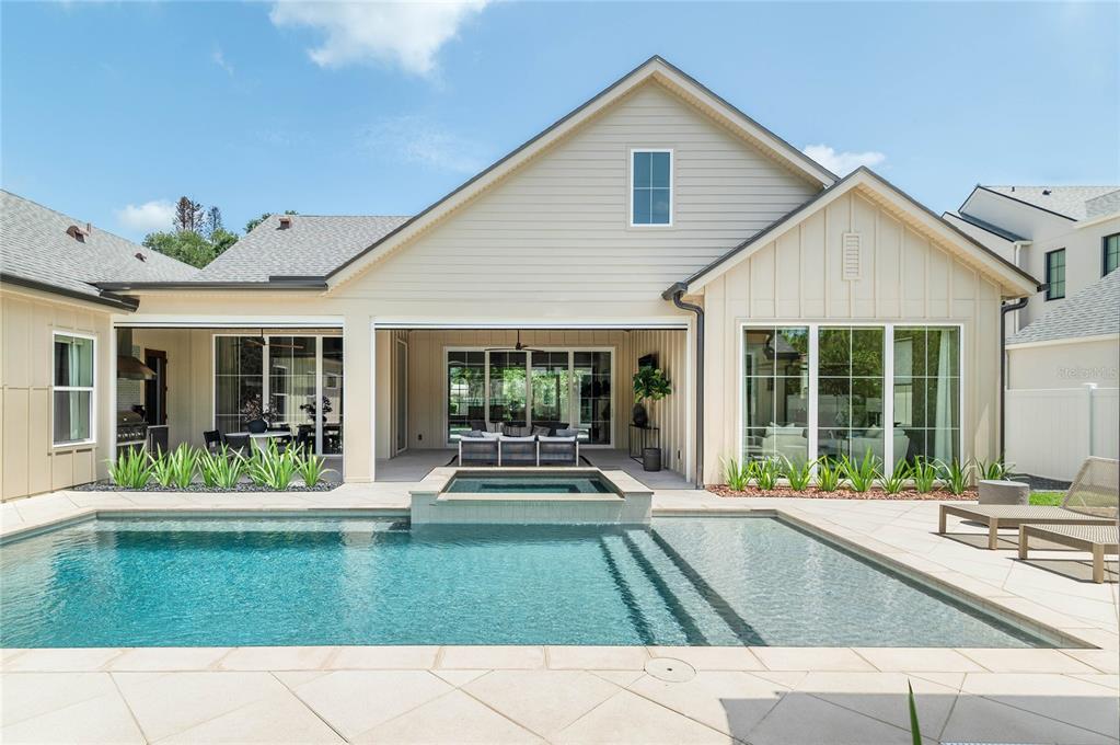 A backyard features a swimming pool with a spa, a covered patio, and light-colored siding — 1204 NOTTINGHAM STREET, ORLANDO, FL