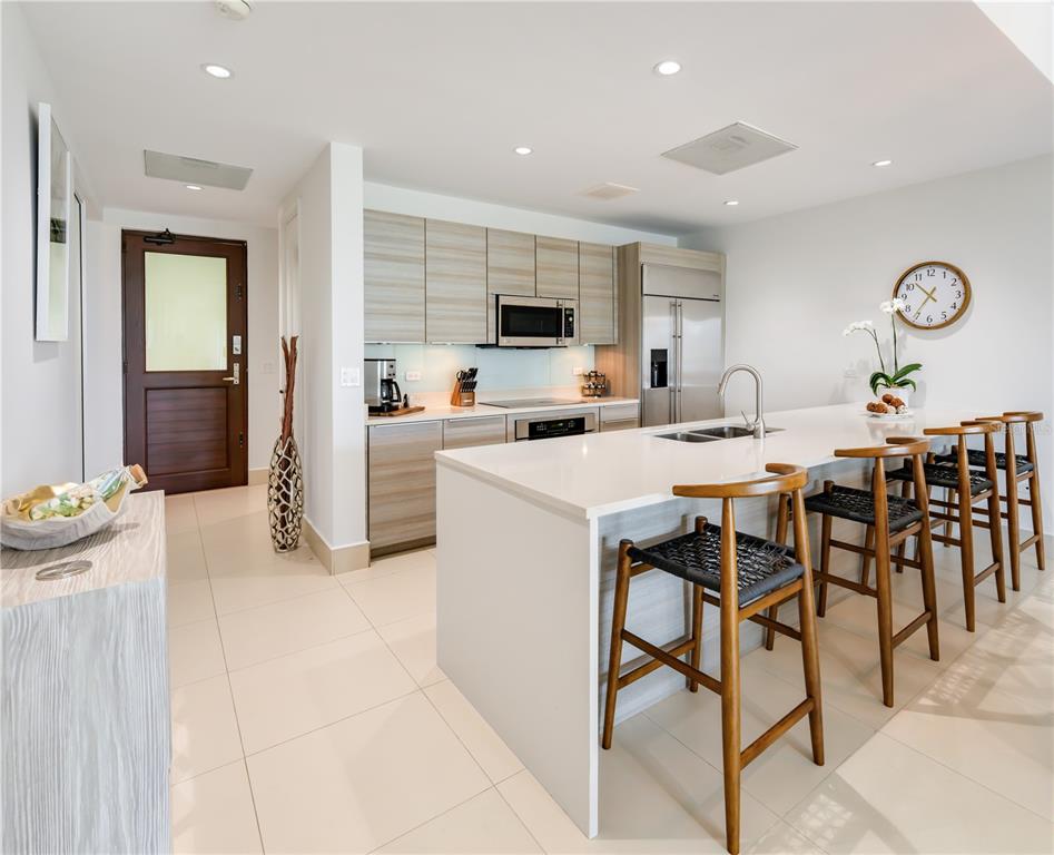 A modern kitchen features light wood cabinetry, a white quartz island, and three bar stools — Ventanas II Condominium 7000 BAHIA BEACH BOULEVARD UNIT 313, RIO GRANDE, PR