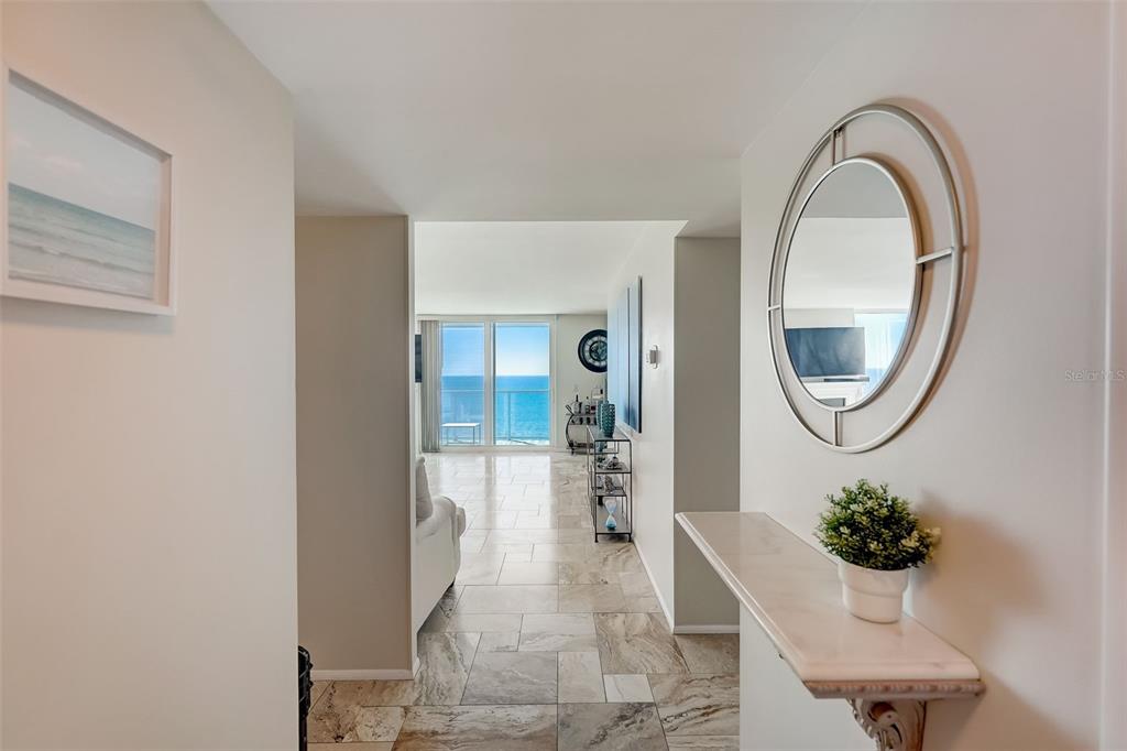 A hallway with marble tile flooring leads to a living area with ocean views — 2425 GULF OF MEXICO DRIVE UNIT 14B, LONGBOAT KEY, FL