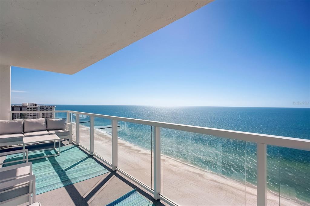 A high-rise balcony features outdoor seating, a glass railing, and a panoramic ocean view — 2425 GULF OF MEXICO DRIVE UNIT 14B, LONGBOAT KEY, FL